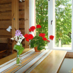 Näkymä pirtin ikkunasta. Pöydällä kauden kukkaloistoa.